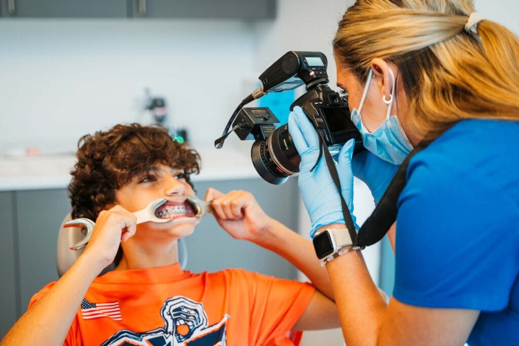 Team member photographing a young patient's smile with cheek retractors